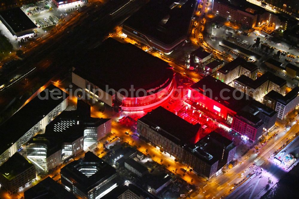 Berlin at night from the bird perspective: Night lighting Arena Mercedes-Benz-Arena on Friedrichshain part of Berlin. The former O2 World - now Mercedes-Benz-Arena - is located in the Anschutz Areal, a business and office space on the riverbank