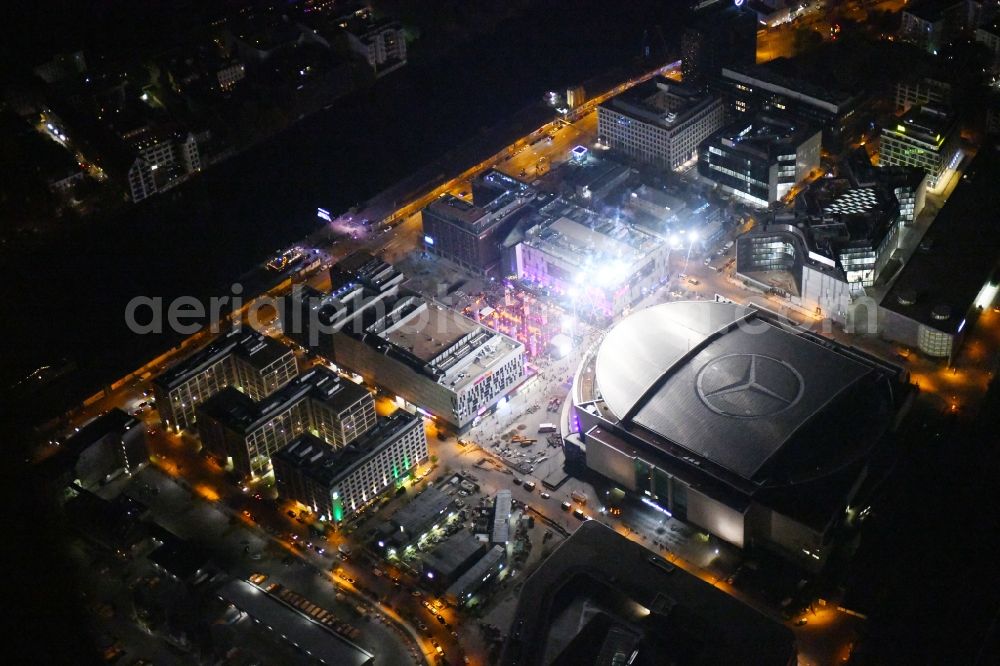 Aerial image at night Berlin - Night lighting Arena Mercedes-Benz-Arena on Friedrichshain part of Berlin. The former O2 World - now Mercedes-Benz-Arena - is located in the Anschutz Areal, a business and office space on the riverbank