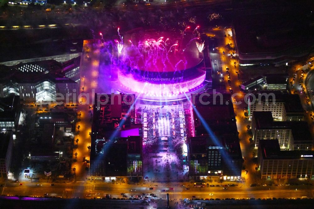 Berlin at night from the bird perspective: Night lighting Arena Mercedes-Benz-Arena on Friedrichshain part of Berlin. The former O2 World - now Mercedes-Benz-Arena - is located in the Anschutz Areal, a business and office space on the riverbank