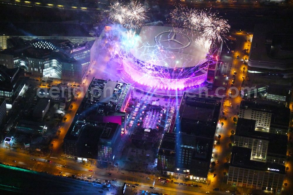 Aerial photograph at night Berlin - Night lighting Arena Mercedes-Benz-Arena on Friedrichshain part of Berlin. The former O2 World - now Mercedes-Benz-Arena - is located in the Anschutz Areal, a business and office space on the riverbank