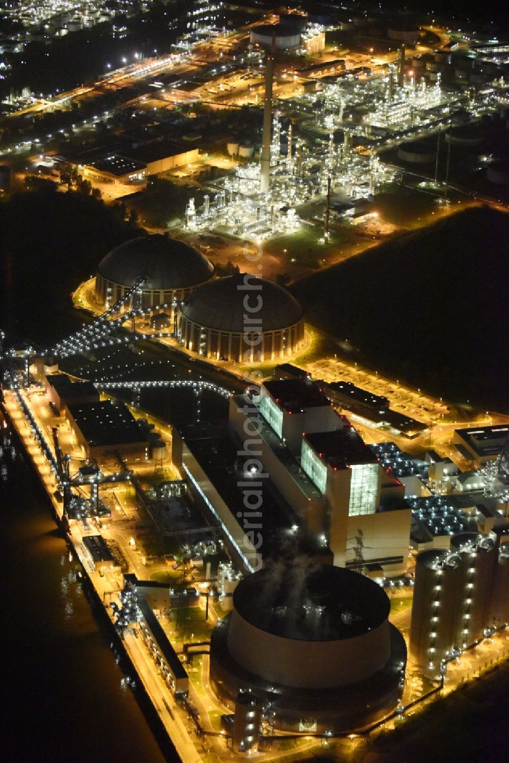 Hamburg at night from the bird perspective: Night view Coal power plants of the Vattenfall power plant Moorburg in Hamburg in Germany. The power plant with its domes, silos and technical facilities is located on the riverbank of the Suederelbe