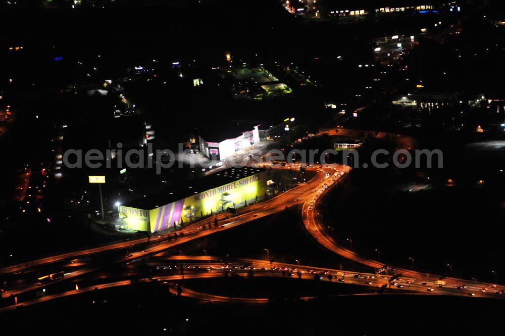 Aerial photograph at night Berlin - Nachtaufnahme: Filiale der Firma Sconto SB – Der Möbelmarkt GmbH in der Grenzallee in Berlin-Neukölln, dahinter die Filiale der Firma SB-MÖBEL BOSS Handelsgesellschaft mbH & Co. KG gegenüber der Autobahnausfahrt Grenzallee der A113 am Autobahndreieck Neukölln. Night shot: Stores of two furniture selling stores at the freeway exit Grenzallee at the motorway junction Neukoelln.