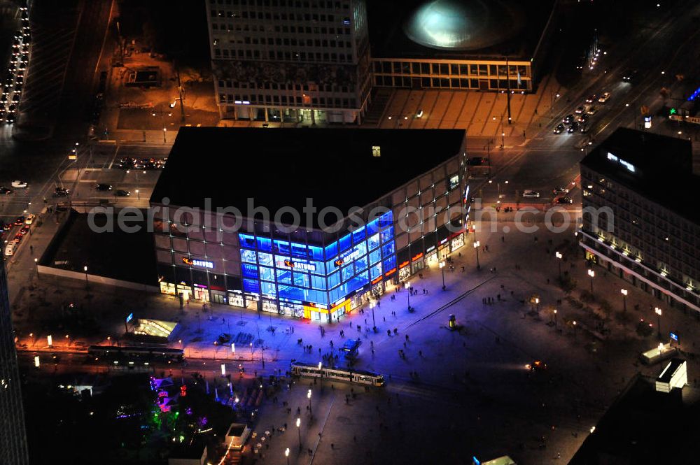 Aerial image at night Berlin - Nachtaufnahme: Blick auf den mit 10.000 Quadratmeter Verkaufsfläche größten Saturn-Markt Deutschlands mit blauer Beleuchtung. Das Elektronik-Unternehmen bezog das neue Geschäftshaus direkt auf dem Alexanderplatz nahe der Kreuzung Alexan derstraße / Karl-Marx-Allee. Night Shot: View to the illuminated Saturn electrical market at the square Alexanderplatz.