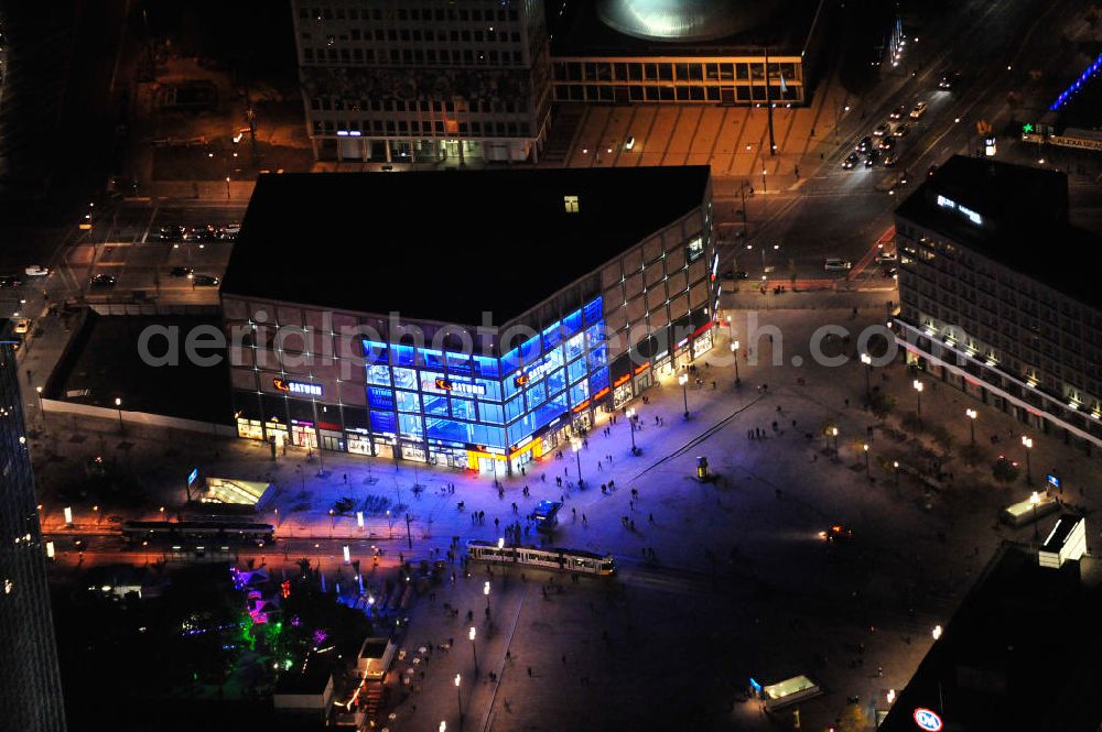 Berlin at night from above - Nachtaufnahme: Blick auf den mit 10.000 Quadratmeter Verkaufsfläche größten Saturn-Markt Deutschlands mit blauer Beleuchtung. Das Elektronik-Unternehmen bezog das neue Geschäftshaus direkt auf dem Alexanderplatz nahe der Kreuzung Alexan derstraße / Karl-Marx-Allee. Night Shot: View to the illuminated Saturn electrical market at the square Alexanderplatz.