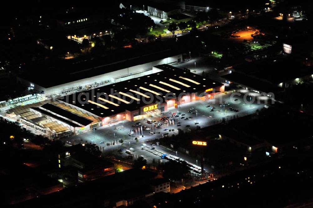 Berlin at night from the bird perspective: Nachtaufnahme: Obi Baumarkt in Berlin-Neukölln an der Grenzallee Ecke Naumburger Straße. Night Shot: Obi DIY market in Berlin-Neukoelln.