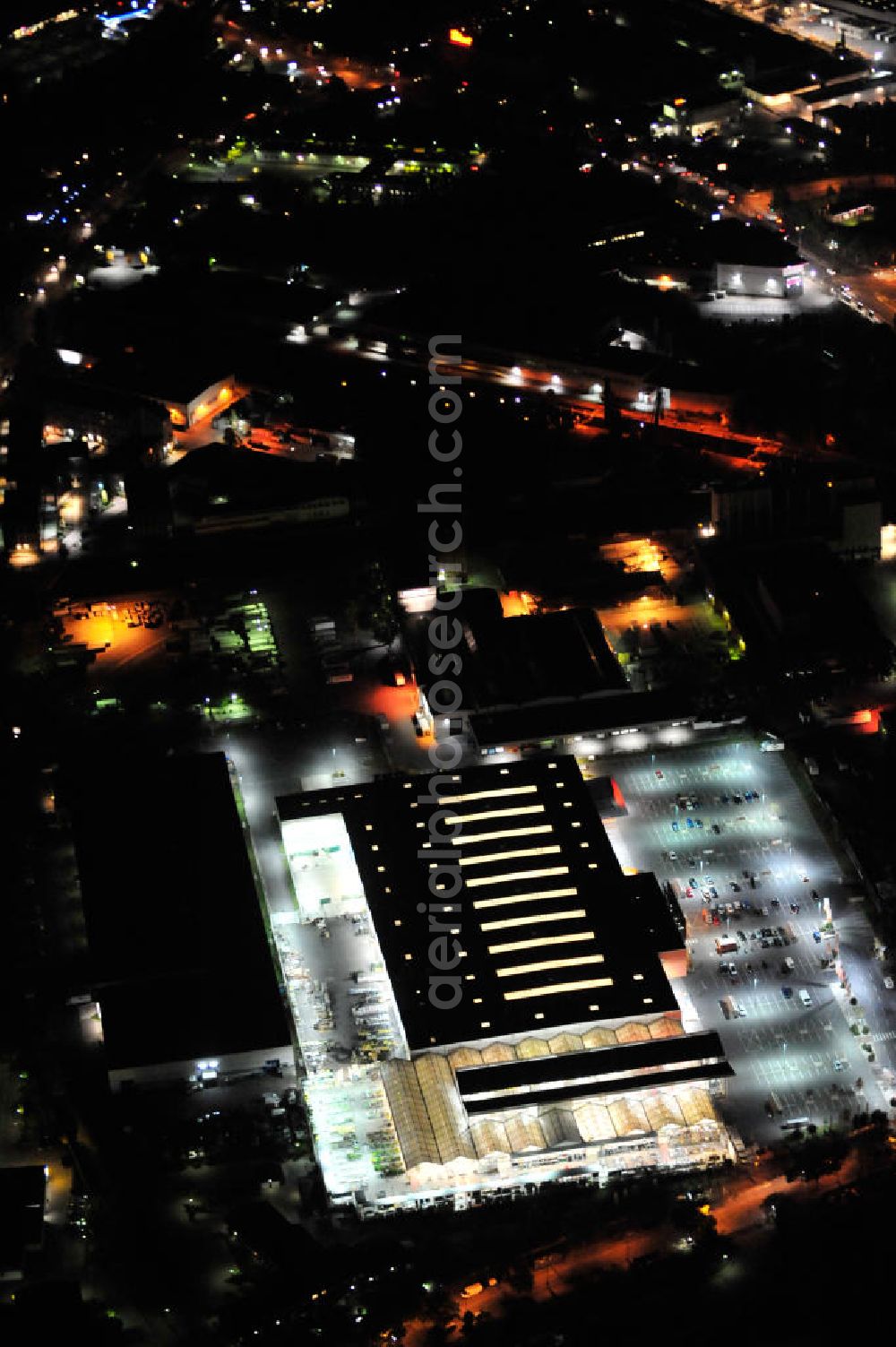 Berlin at night from the bird perspective: Nachtaufnahme: Obi Baumarkt in Berlin-Neukölln an der Grenzallee Ecke Naumburger Straße. Night Shot: Obi DIY market in Berlin-Neukoelln.