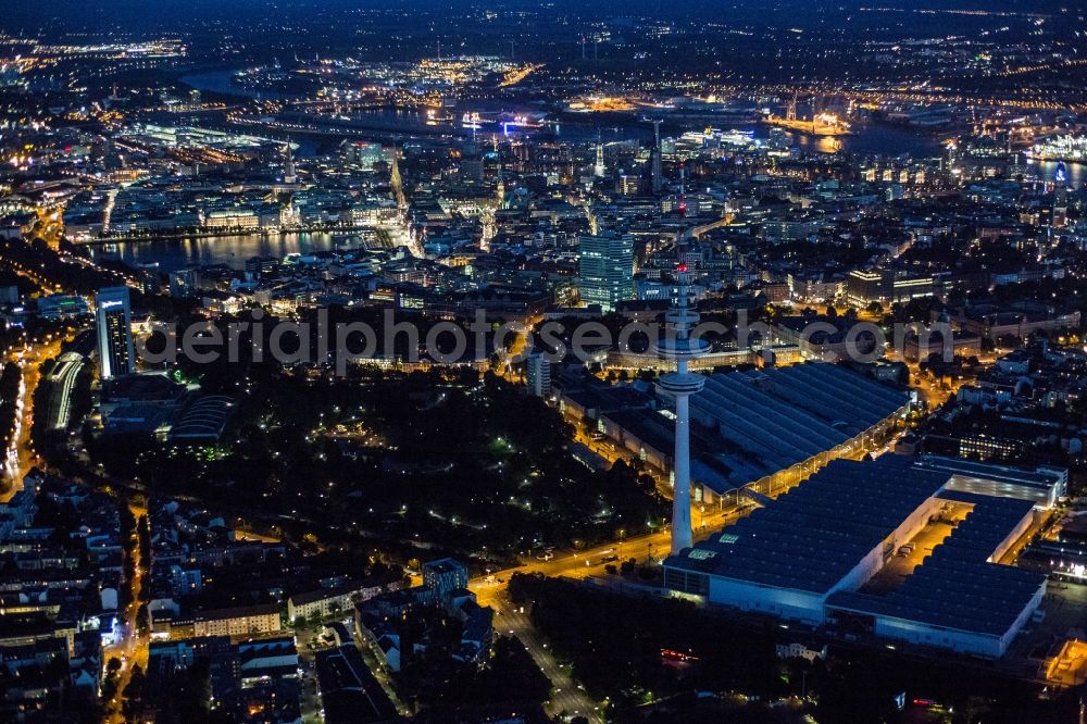 Hamburg at night from the bird perspective: Night Aerial city view of the Heinrich-Hertz-Turm and Planten un Bloomen, overlooking the Alster Lake and the harbor in the northern Elbe. The TV Tower Heinrich-Hertz-Turm shapes the cityscape as the tallest building in Hamburg. In the adjacent city park Planten un Bloomen there are different themed gardens and landscapes to be found, including the Old Botanical Garden Hamburg