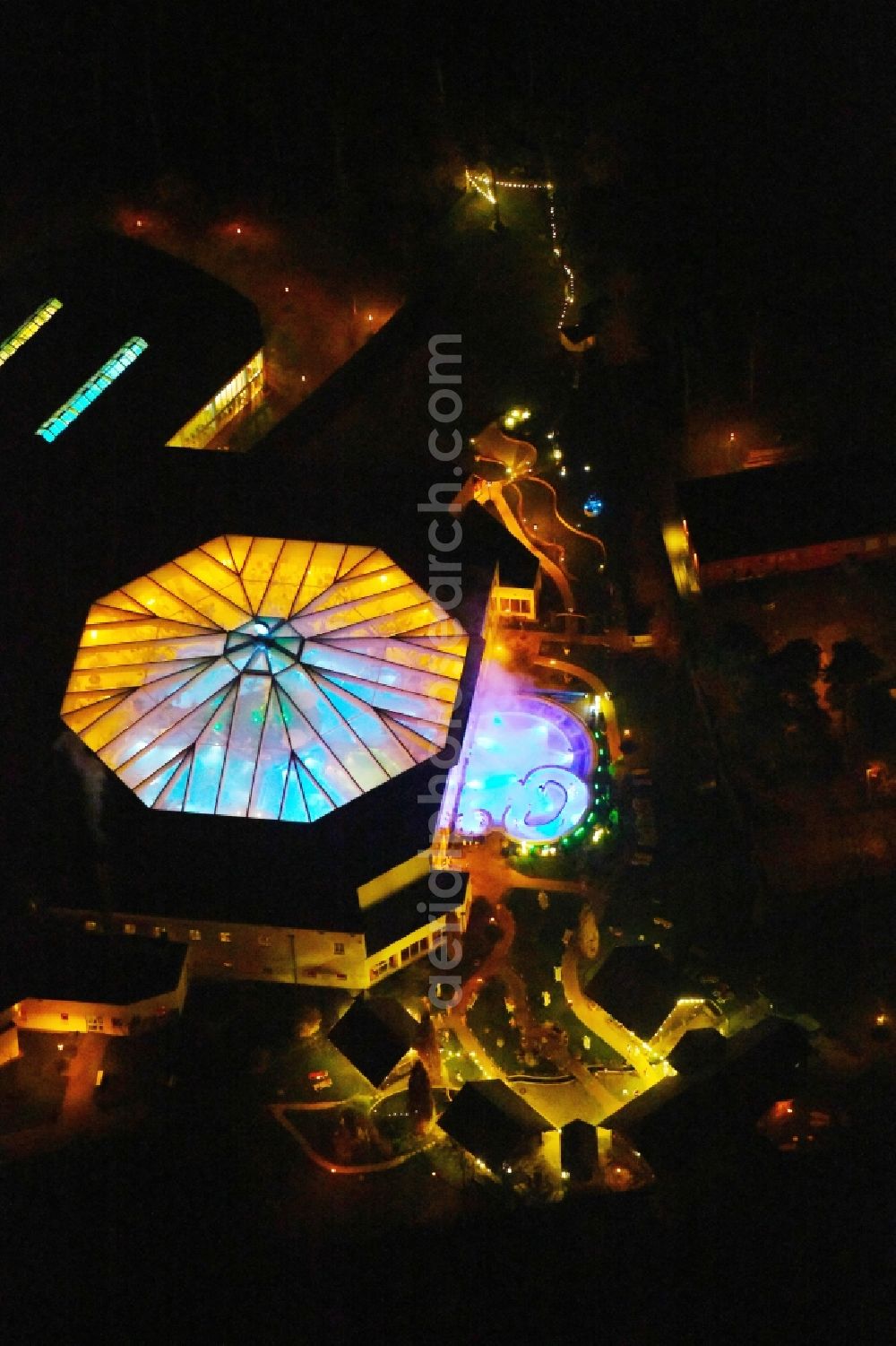 Ludwigsfelde at night from the bird perspective: Night lighting Spa and swimming pools at the swimming pool of the leisure facility of Kristall Baeof AG in Ludwigsfelde in the state Brandenburg, Germany