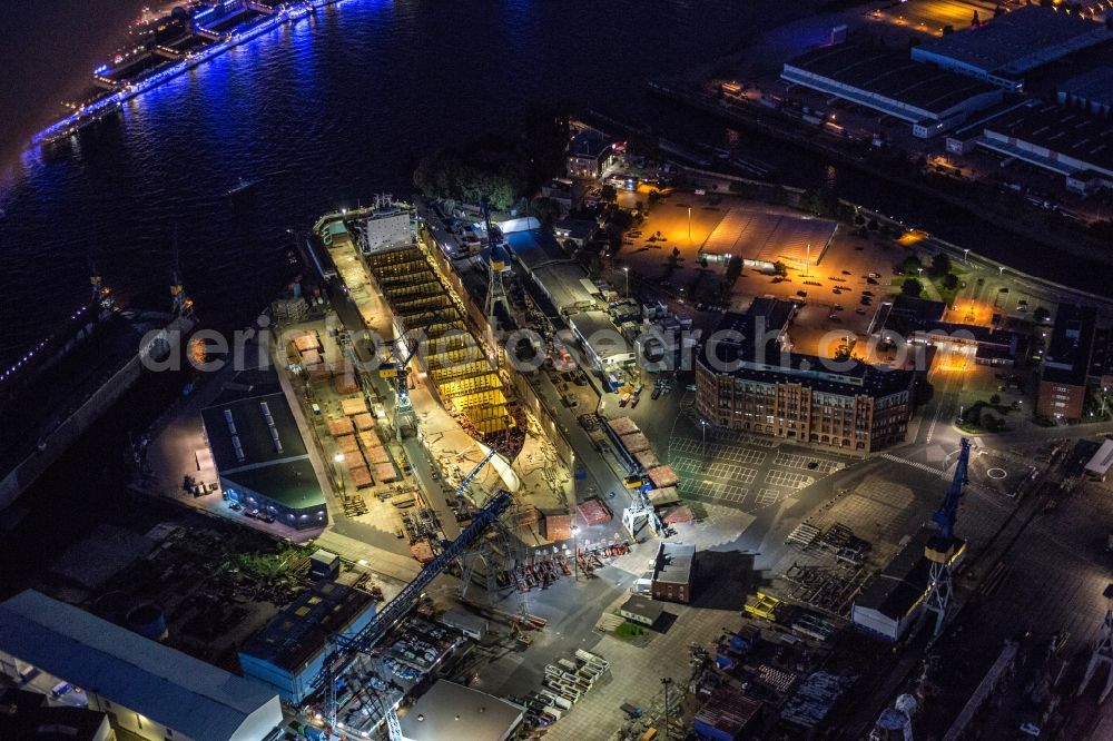 Hamburg at night from the bird perspective: Night view of installation work on a tanker hull in dry dock / Blohm and Voss Dock Elbe in Hamburg. Clearly visible are the different sections of the Scots and future tanker. The dry dock Elbe 17 is one of the largest dry dock in Europe. It is located on the grounds of the Blohm + Voss shipyard in Hamburg