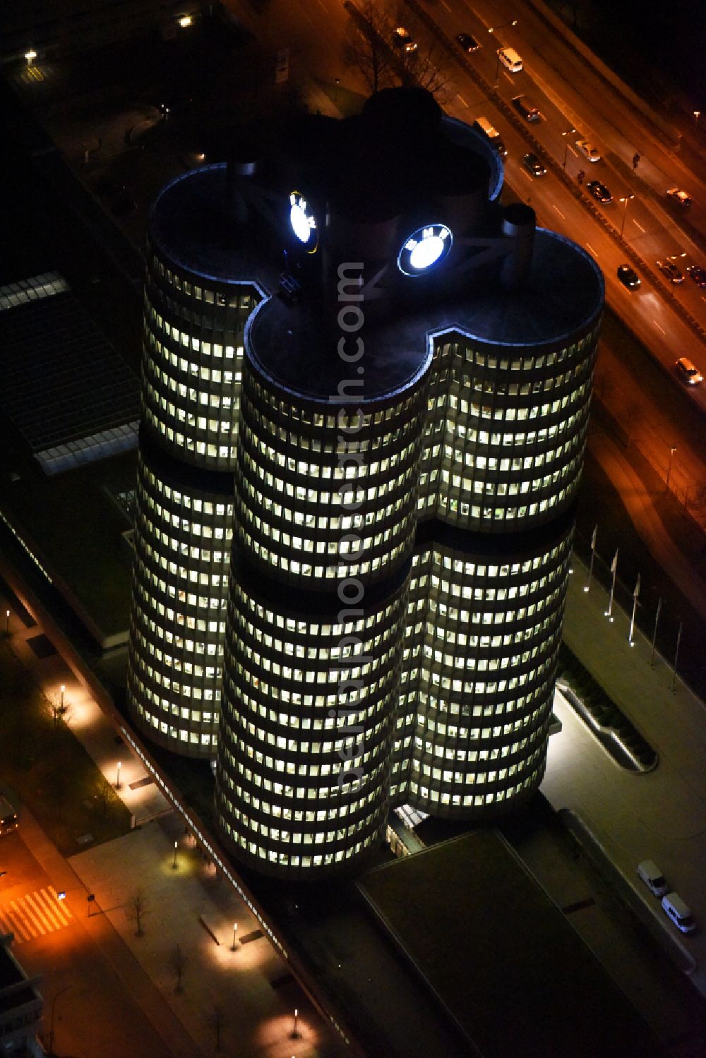 Aerial photograph at night München - Night lighting administration building of the company Vierzylinof of BMW AG in the district Milbertshofen-Am Hart in Munich in the state Bavaria, Germany