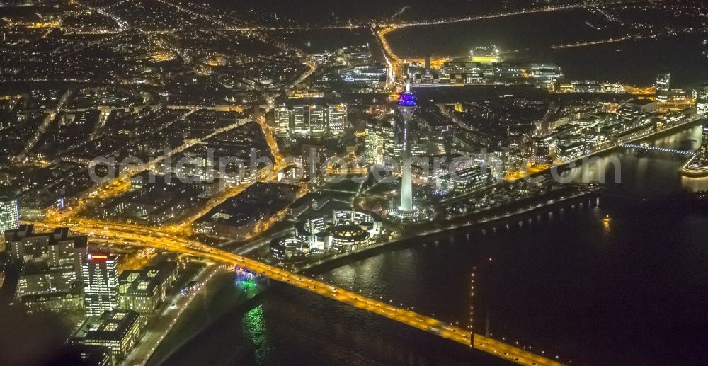 Düsseldorf at night from the bird perspective: View of the telecommunications tower Rheinturm in Dusseldorf in the state North Rhine-Westhalia. The Rheinturm carries aerials for directional radio, FM and TV transmitters and DVB-T