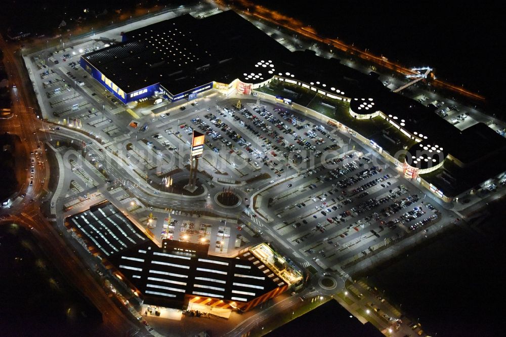 Lübeck at night from the bird perspective: Night view building of the store - furniture market IKEA der IKEA Deutschland GmbH & Co. KG in Luebeck in the state Schleswig-Holstein. On the ground as well a HORNBACH building supplies store and the LUVSHOPPING shopping centre