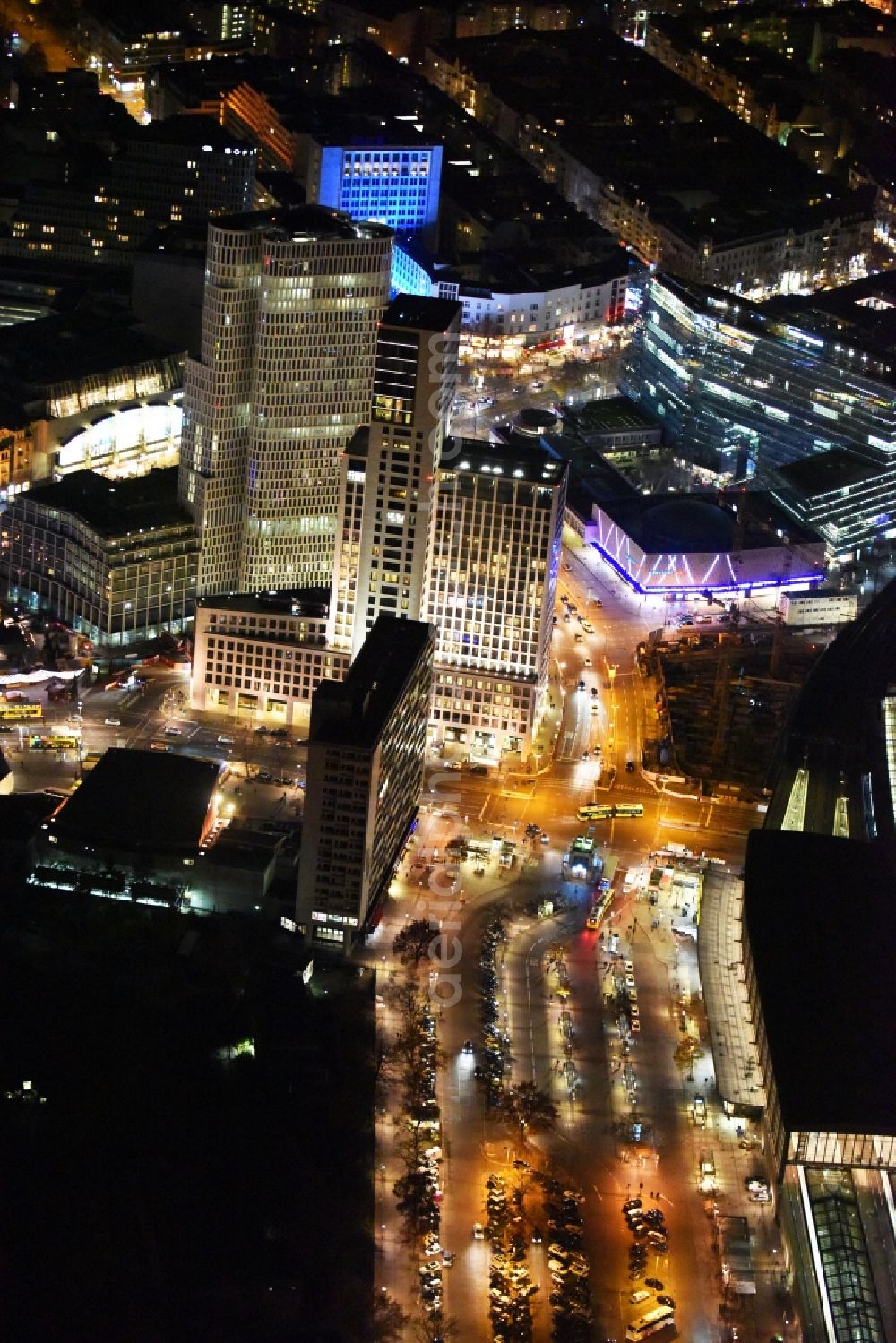 Berlin at night from above - Night view group of buildings alongside the S-Bahn-track between the streets Kurfuerstendamm und Kantstrasse in the district Berlin Charlottenburg. You can see the CityQuartier Neues Kanzler-Eck, the highrise Zoofenster and the church Kaiser-Wilhelm-Gedaechtniskirche