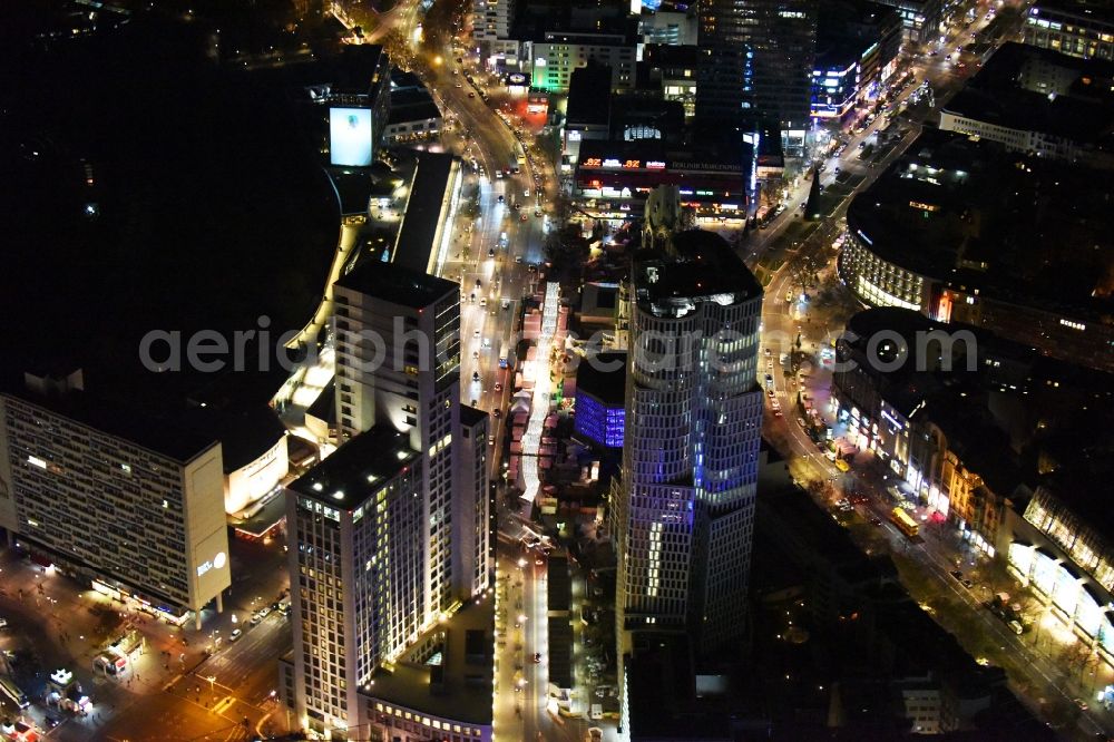 Berlin at night from above - Night view group of buildings alongside the S-Bahn-track between the streets Kurfuerstendamm und Kantstrasse in the district Berlin Charlottenburg. You can see the CityQuartier Neues Kanzler-Eck, the highrise Zoofenster and the church Kaiser-Wilhelm-Gedaechtniskirche