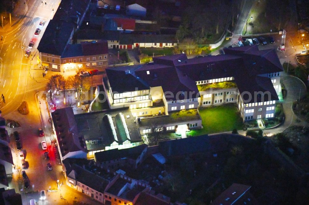 Strausberg at night from the bird perspective: Night lighting Banking administration building of the financial services company Sparkasse on Karl-Liebknecht-Strasse coner Grosse Strasse in Strausberg in the state Brandenburg, Germany