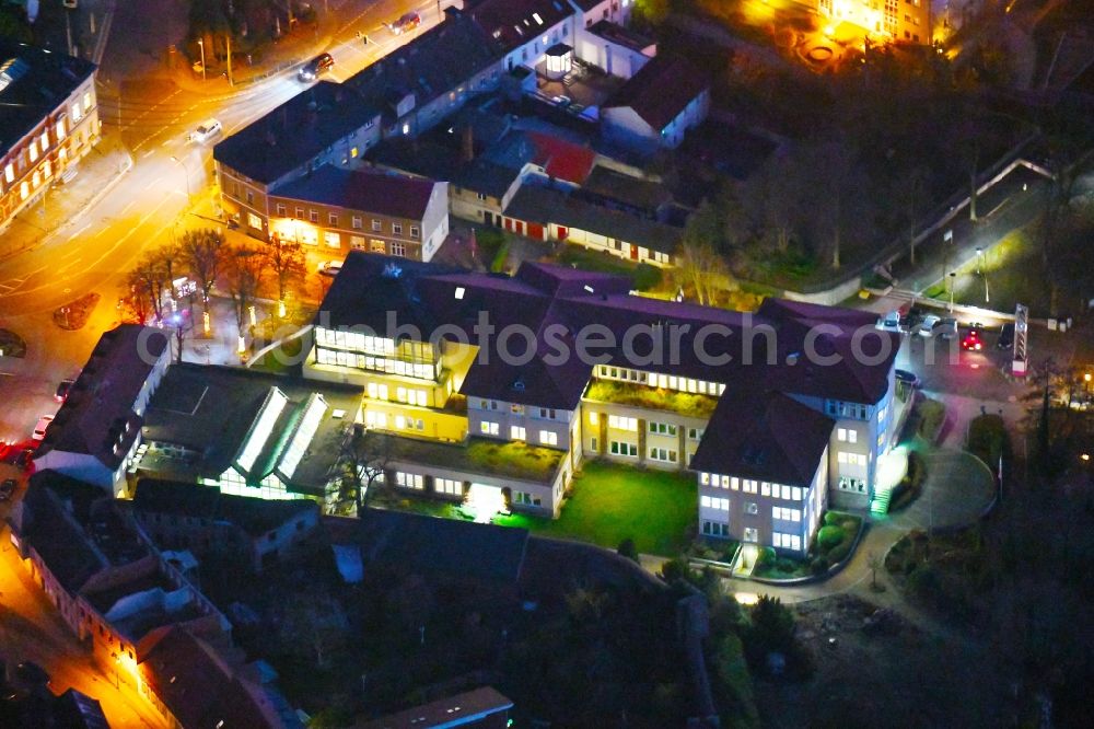 Strausberg at night from the bird perspective: Night lighting Banking administration building of the financial services company Sparkasse on Karl-Liebknecht-Strasse coner Grosse Strasse in Strausberg in the state Brandenburg, Germany