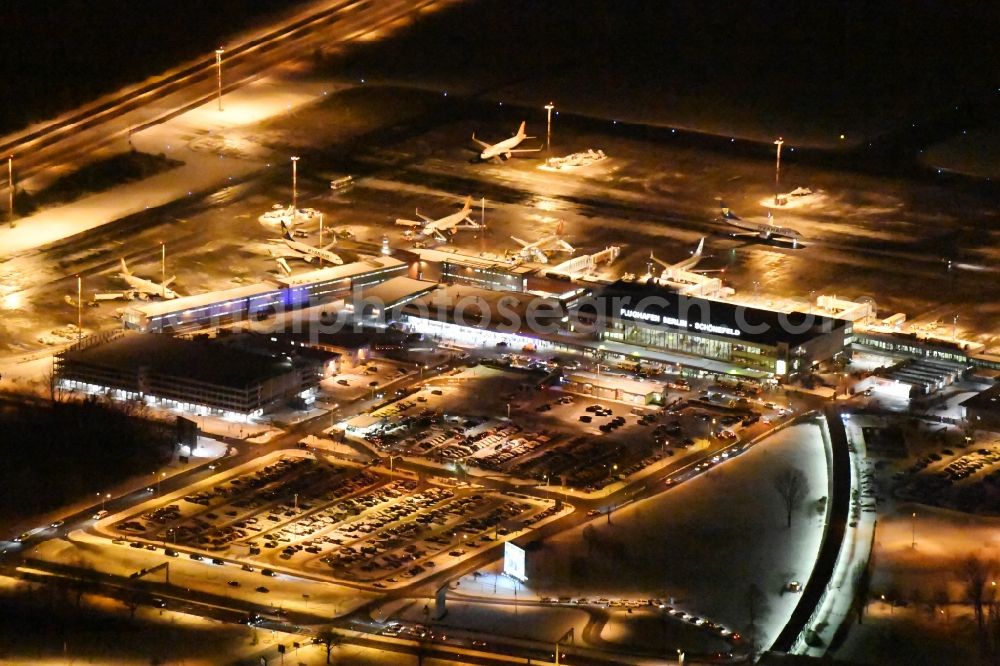 Schönefeld at night from the bird perspective: Night image of wintry snowy area and main building of the airport Berlin-Schoenefeld SXF in Schoenefeld in the state of Brandenburg