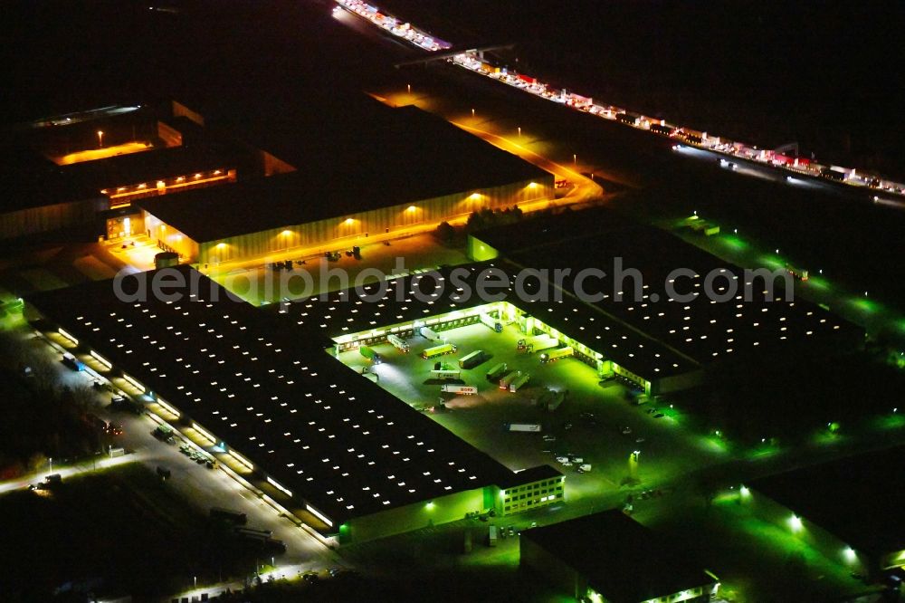 Aerial image at night Ludwigsfelde - Night lighting Building and production halls on the premises of FIEGE Logistik Stiftung & Co. KG Am Birkengrund in Ludwigsfelde in the state Brandenburg, Germany