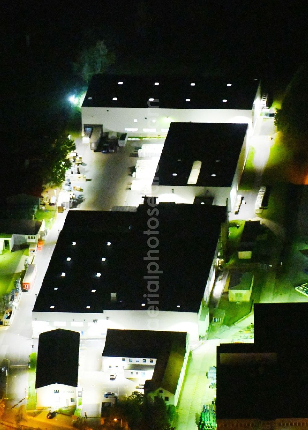 Radeburg at night from the bird perspective: Night lighting building and production halls on the premises of Mitras GmbH on Bahnhofstrasse in Radeburg in the state Saxony, Germany