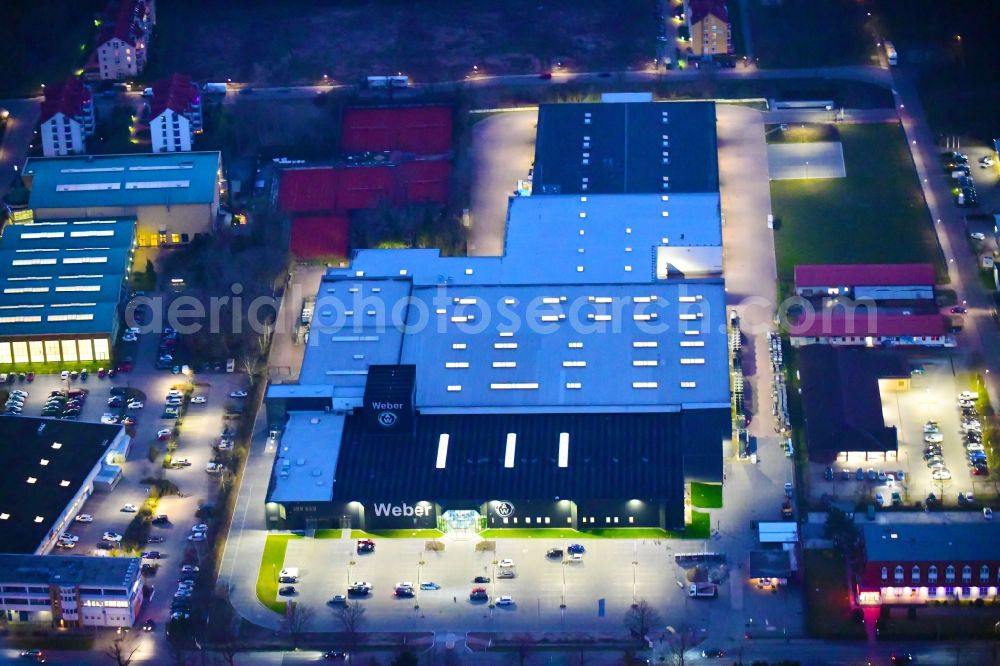 Bernau at night from the bird perspective: Night lighting building and production halls on the premises of Weber Automotive GmbH in Bernau in the state Brandenburg, Germany