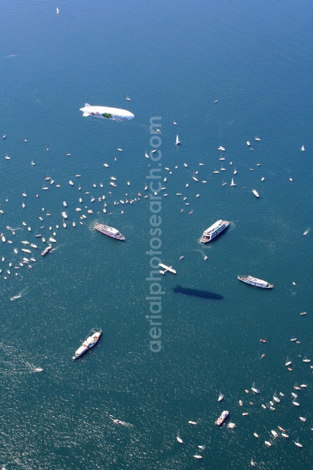 Aerial photograph Friedrichshafen - Between Romanshorn in Switzerland and Friedrichshafen in Germany 2500 ships form a bridge of boats to commemorate the help of the Swiss people for the German post-war children 60 years ago. In the middle of the lake, a large Swiss cross was formed by large vessels. In the middle of the cross the historic flying boat Do 24