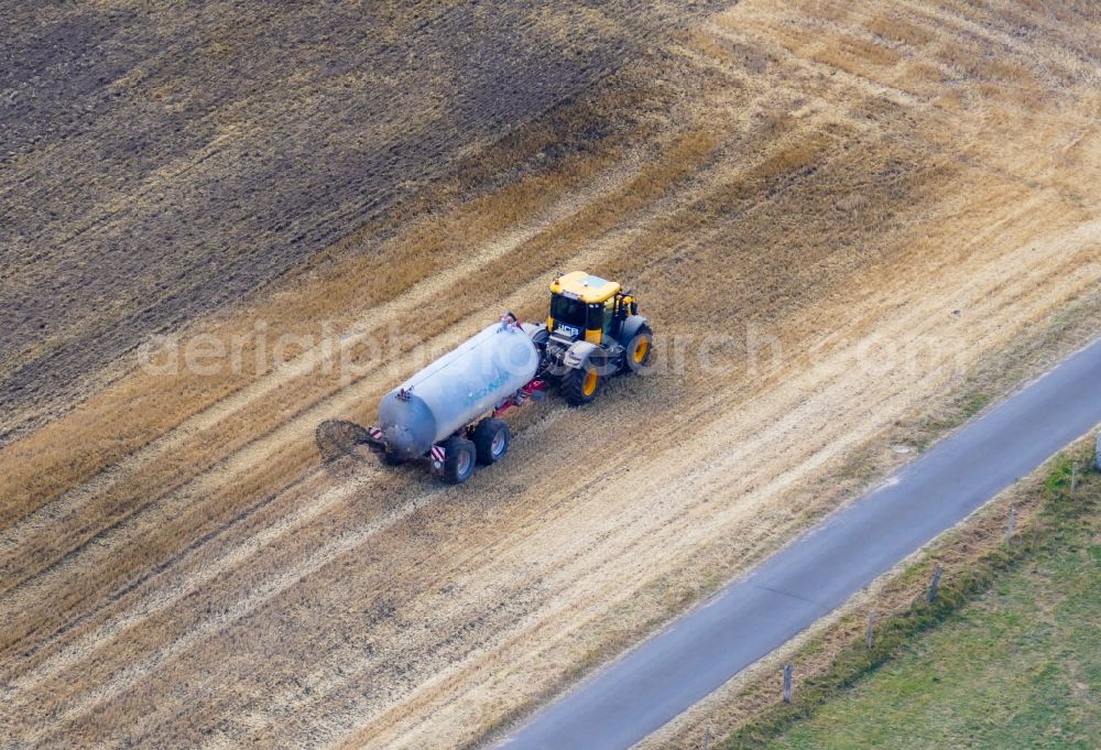 Friedland from the bird's eye view: Spraying manure as fertilizer with tractor and tank trailer on agricultural fields in Friedland in the state Lower Saxony, Germany