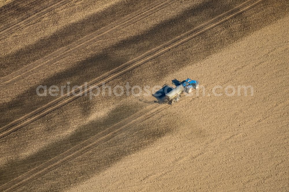 Friedrichsfeld from the bird's eye view: Spraying manure as fertilizer with tractor and tank trailer on agricultural fields in Friedrichsfeld in the state North Rhine-Westphalia, Germany