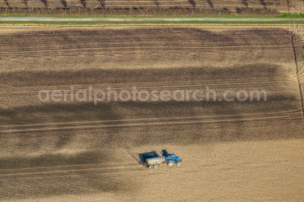 Aerial image Friedrichsfeld - Spraying manure as fertilizer with tractor and tank trailer on agricultural fields in Friedrichsfeld in the state North Rhine-Westphalia, Germany