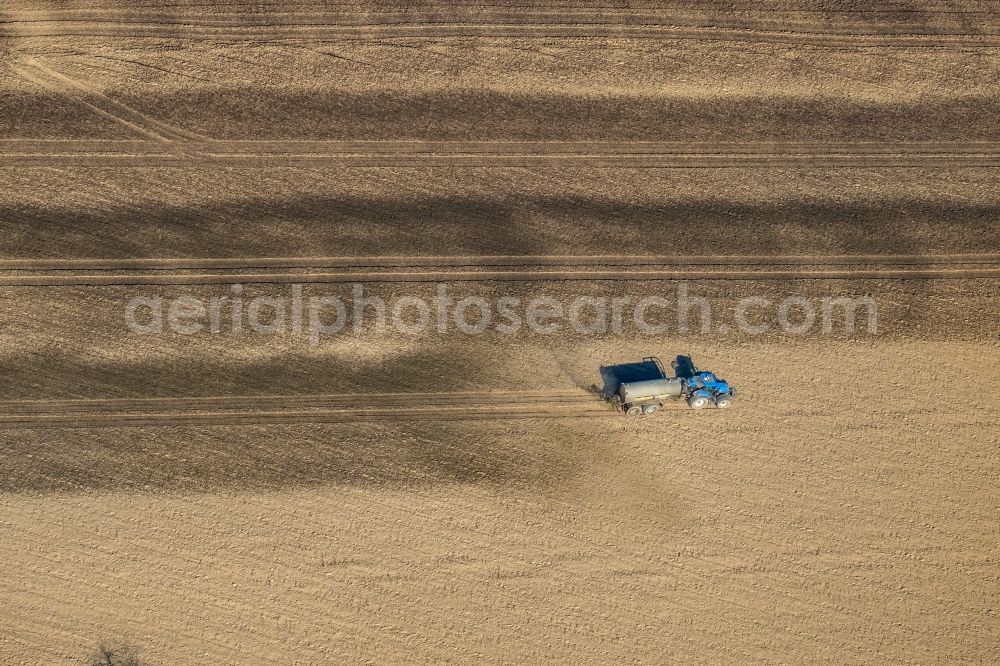 Aerial photograph Friedrichsfeld - Spraying manure as fertilizer with tractor and tank trailer on agricultural fields in Friedrichsfeld in the state North Rhine-Westphalia, Germany