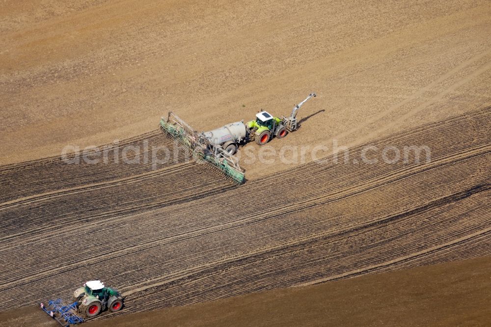 Aerial photograph Göttingen - Spraying manure as fertilizer with tractor and tank trailer on agricultural fields in Goettingen in the state Lower Saxony, Germany