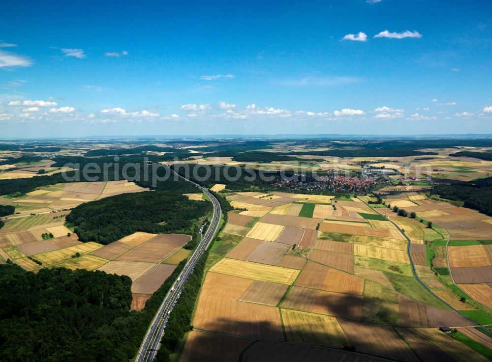 Helmstadt from above - Bundesautobahn (federal motorway) A3 and landscape near Helmstadt in the state of Bavaria. The autobahn runs from the West to the East and is surrounded by fields, agricultural spaces and forest. Helmstadt is located in the South of the motorway