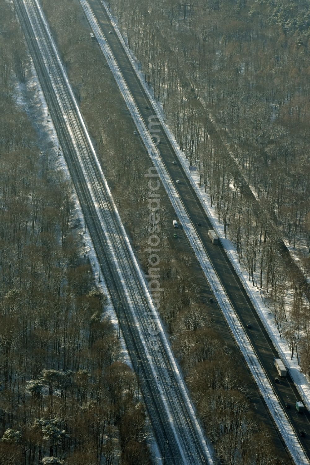 Aerial photograph Berlin - Snow covered course of the federal motorway A115 in the Southern Grunewald forest area in the district of Steglitz-Zehlendorf in Berlin in Germany. Railway tracks are running parallel to the road