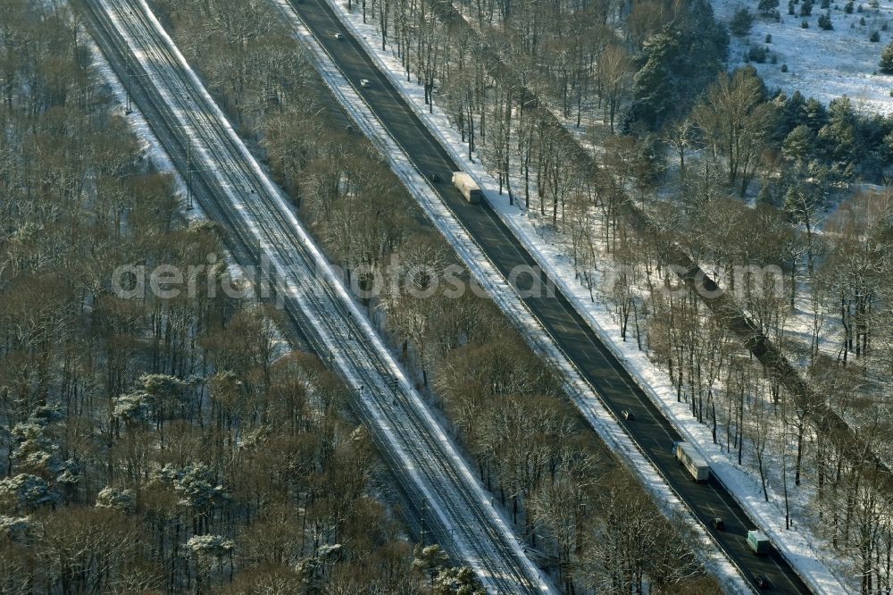 Berlin from the bird's eye view: Snow covered course of the federal motorway A115 in the Southern Grunewald forest area in the district of Steglitz-Zehlendorf in Berlin in Germany. Railway tracks are running parallel to the road