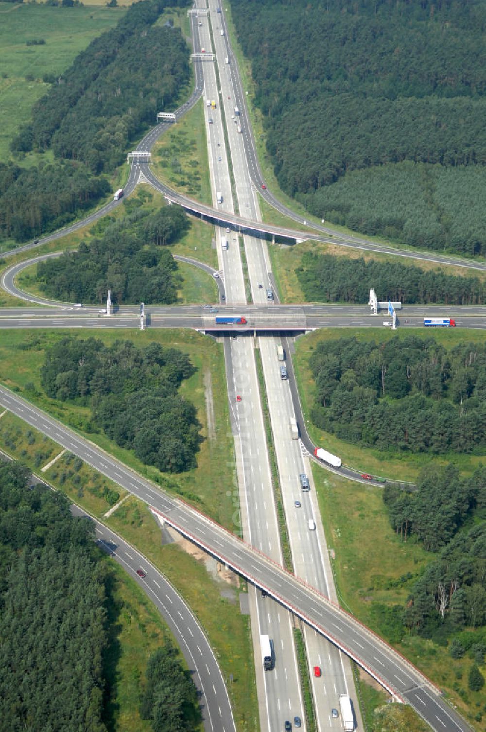 Aerial photograph Schönefeld - Blick auf das Autobahnkreuz Schönefeld. Das Schönefelder Kreuz (umgangssprachlich auch Kreuz Schönefeld) ist ein Autobahnkreuz am südlichen Berliner Ring (A 10), der nach Süden die A 13 Dresden und nach Norden die A 113 Berlin anbindet. Das Kreuz wurde ursprünglich in der verbreiteten Kleeblattform errichtet, wobei drei sehr enge Kreisel (Tempo: 20 bis 40 km/h) gesetzt wurden, bis zur Wende fehlte sogar eine Tangente (Durchfahren von drei Kreiseln notwendig). Lediglich der Kreisel im nordwestlichen Quadranten des Autobahnkreuzes wurde überdimensioniert - in Relation zum gesamten Autobahnkreuz - errichtet. Der Umbau des Schönefelder Kreuzes in den 1990ern brachte eine Mischform hervor, die in Richtung eines Malteserkreuzes geht, der Wechsel Nord nach Ost und Süd nach West hat jedoch weiterhin enge Kreisel.