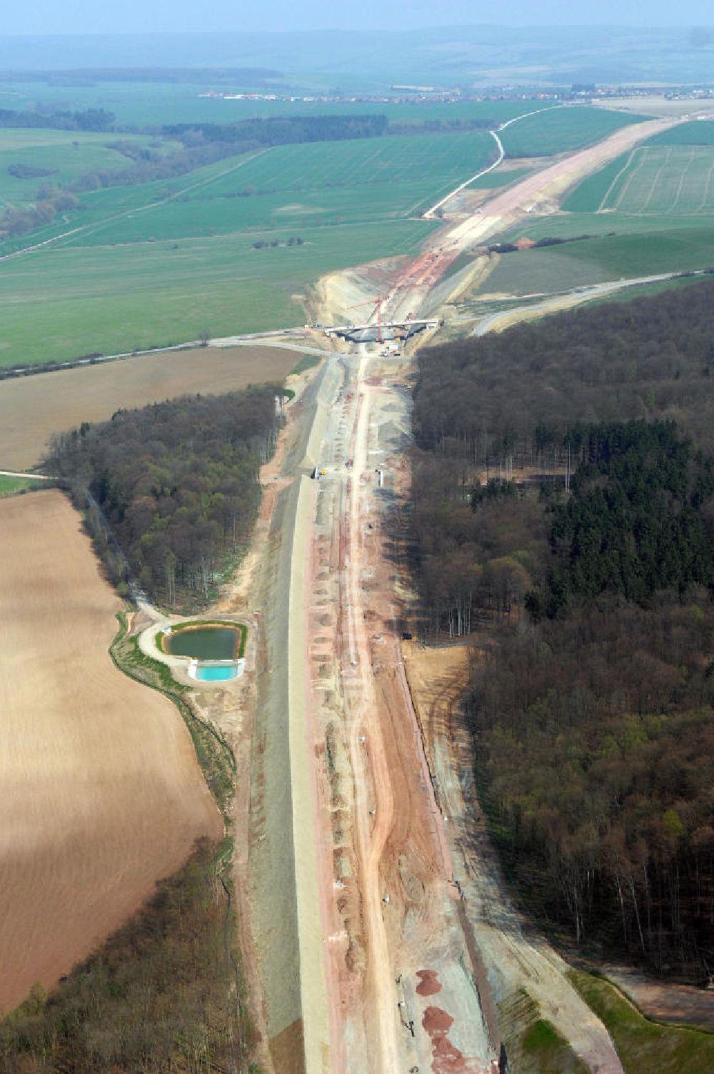 Madelungen from above - Blick auf die Baustelle der A4 im Madelunger Forst mit einem Regenrückhaltebecken, einer Unterführung sowie einer Strassenbrücke südlich von Madelungen. Für die Autobahn wurden in diesem Buchen-Wald ca. 12 Hektar Bäume abgeholzt. Der Neubau ist Teil des Projekt Nordverlegung / Umfahrung Hörselberge der Autobahn E40 / A4 in Thüringen bei Eisenach. Durchgeführt werden die im Zuge dieses Projektes notwendigen Arbeiten unter an derem von den Mitarbeitern der Niederlassung Weimar der EUROVIA Verkehrsbau Union sowie der Niederlassungen Abbruch und Erdbau, Betonstraßenbau, Ingenieurbau und TECO Schallschutz der EUROVIA Beton sowie der DEGES.