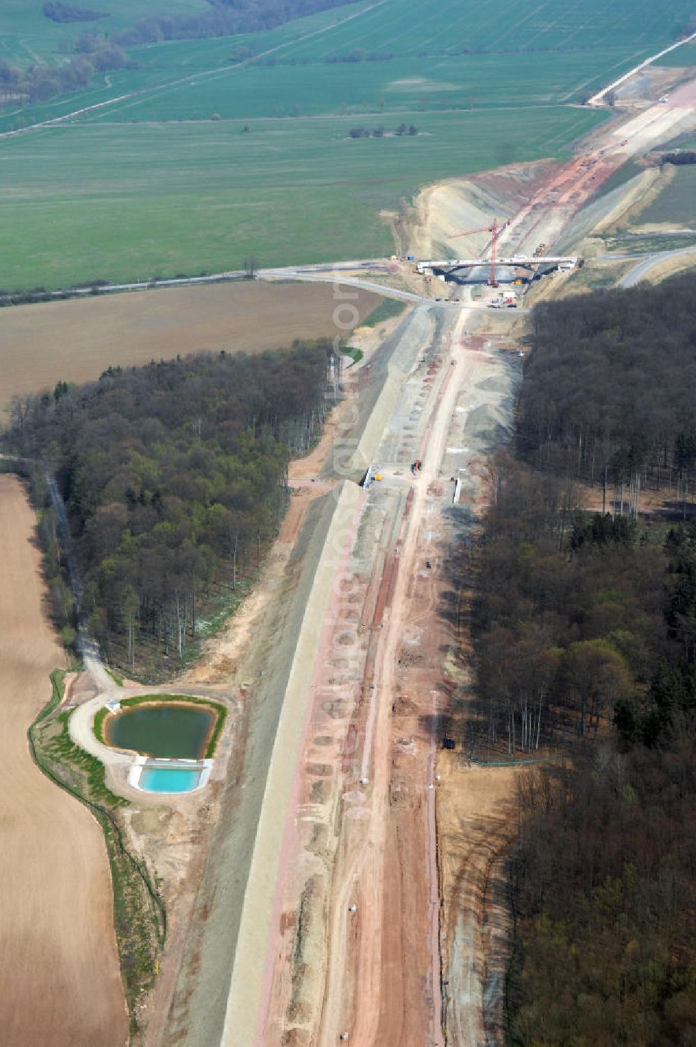 Madelungen from the bird's eye view: Blick auf die Baustelle der A4 im Madelunger Forst mit einem Regenrückhaltebecken, einer Unterführung sowie einer Strassenbrücke südlich von Madelungen. Für die Autobahn wurden in diesem Buchen-Wald ca. 12 Hektar Bäume abgeholzt. Der Neubau ist Teil des Projekt Nordverlegung / Umfahrung Hörselberge der Autobahn E40 / A4 in Thüringen bei Eisenach. Durchgeführt werden die im Zuge dieses Projektes notwendigen Arbeiten unter an derem von den Mitarbeitern der Niederlassung Weimar der EUROVIA Verkehrsbau Union sowie der Niederlassungen Abbruch und Erdbau, Betonstraßenbau, Ingenieurbau und TECO Schallschutz der EUROVIA Beton sowie der DEGES.