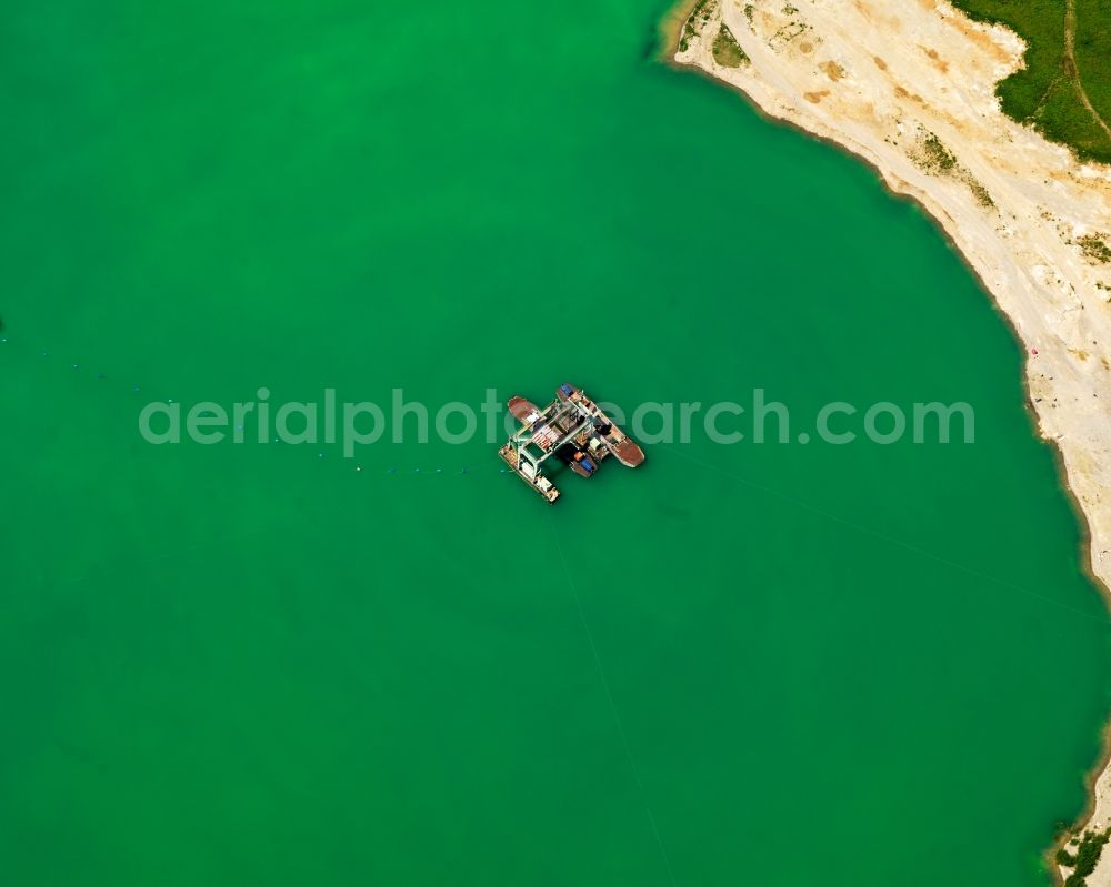 Aerial image Breisach am Rhein - Quarry pond near Guendlingen in Breisbach on Rhine in the state of Baden-Wuerttemberg. There are four large excavated lakes in the area. They are surrounded by a sand shore. A digger is situated on the lake