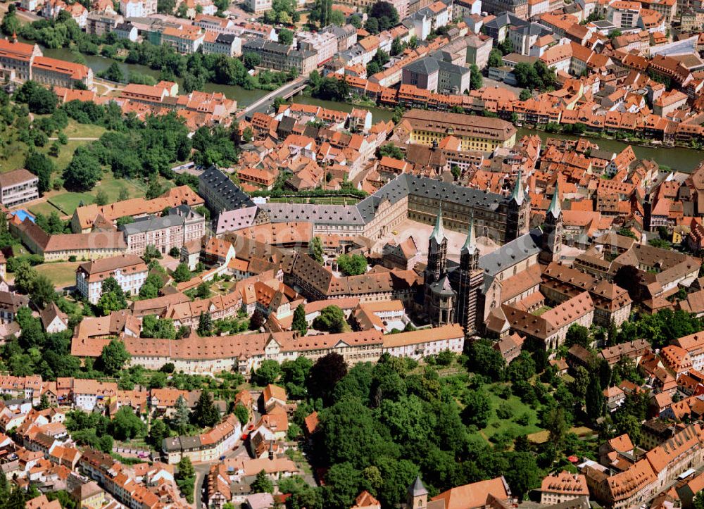 Aerial image Bamberg - Der Bamberger Dom mit seinen vier Türmen gilt als eines der schönsten mittelalterlichen Bauwerke. Das Alte Rathaus liegt geduckt links vom Dom und die Neue Residenz ist gegenüber sichtbar. Bamberg (mittelalterlich: Babenberg, bambergisch: Bambärch) ist eine kreisfreie Stadt im bayerischen Regierungsbezirk Oberfranken und gleichzeitig Standort des Landratsamtes Bamberg. Bamberg ist Universitäts-, Schul- und Verwaltungsstadt, wichtiges Wirtschaftszentrum Oberfrankens, sowie Sitz des gleichnamigen Erzbistums. Die Stadt ist in der Landesplanung als Oberzentrum des westlichen Oberfranken ausgewiesen und ist Mitglied in der Metropolregion Nürnberg. Bamberg ist Mittelpunkt eines Ballungsraums von über 200.000 Einwohnern und gilt als wichtigstes Zentrum im oberfränkischen Raum. Die sehenswerte Altstadt besitzt den größten unversehrt erhaltenen historischen Stadtkern in Deutschland und ist seit 1993 als Weltkulturerbe in die Liste der UNESCO eingetragen. Darüber hinaus ist Bamberg überregional bekannt für seine vielfältige und eigenständige Biertradition.