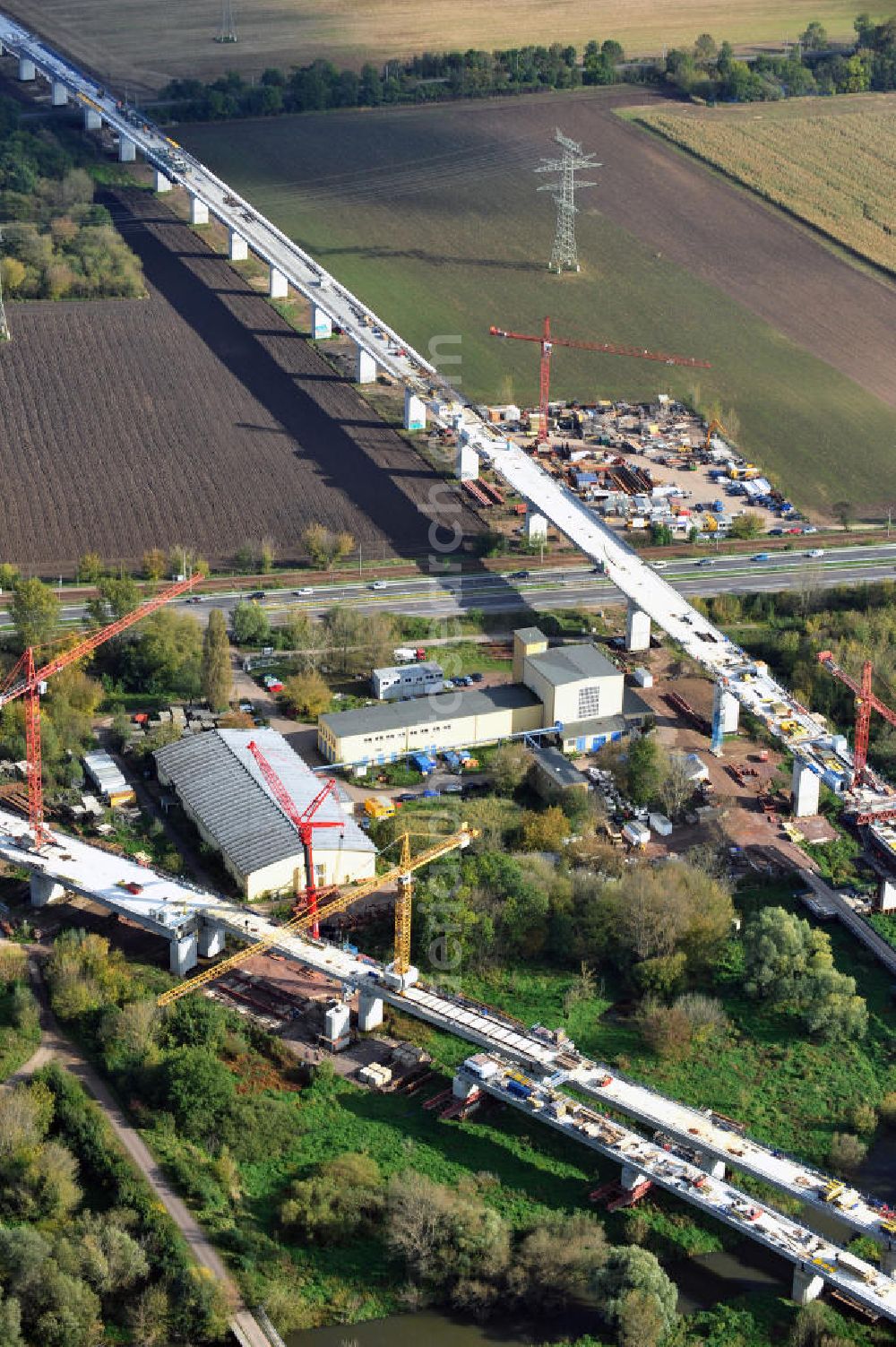 Aerial image Rattmannsdorf - Vorschub- Bauarbeiten an der Saale-Elster-Talbrücke zwischen Ammendorf und Schkopau. Das Beton- Viadukt mit insgesamt 8, 5 Kilometern Länge wird teilweise mit großen Baugerüsten in so genannter Vor-Kopf-Bauweise errichtet. Die ICE - Neubaustrecke im Projekt VDE 8 der Deutschen Bahn und der DEGES soll 2015 in Betrieb gehen und wird das bisher längste Brückenbauwerk Deutschlands sein. Bauausführende Firmen sind die Hochtief Construction AG, Adam Hörnig, Gerdum und Breuer; Franki Grundbau; Doka Schalungstechniker; BBV Vorspanntechnik; Röro Traggerüstsysteme; Oevermann Hoch- und Tiefbau, Teupe & Söhne Gerüstbau GmbH, Alpine Bau, Kann Baustoffe und Arcelormittal. Die Bauüberwachung erfolgt durch das Ingenieurbüro Schüßler Plan. Construction site of the Saale-Elster-Talbrücke between Ammendorf and Schkopau. It will be 8, 5 km long and belongs to the Deutsche Bahn project VDE 8 and the DEGES. It should be finished in 2015. Its going to be the longest bridge in Germany. It is constructed by Hochtief Construction AG, Adam Hörnig, Gerdum und Breuer; Franki Grundbau; Doka Schalungstechniker; BBV Vorspanntechnik; Röro Traggerüstsysteme; Oevermann Hoch- und Tiefbau, Teupe & Söhne Gerüstbau GmbH, Alpine Bau, Kann Baustoffe und Arcelormittal.