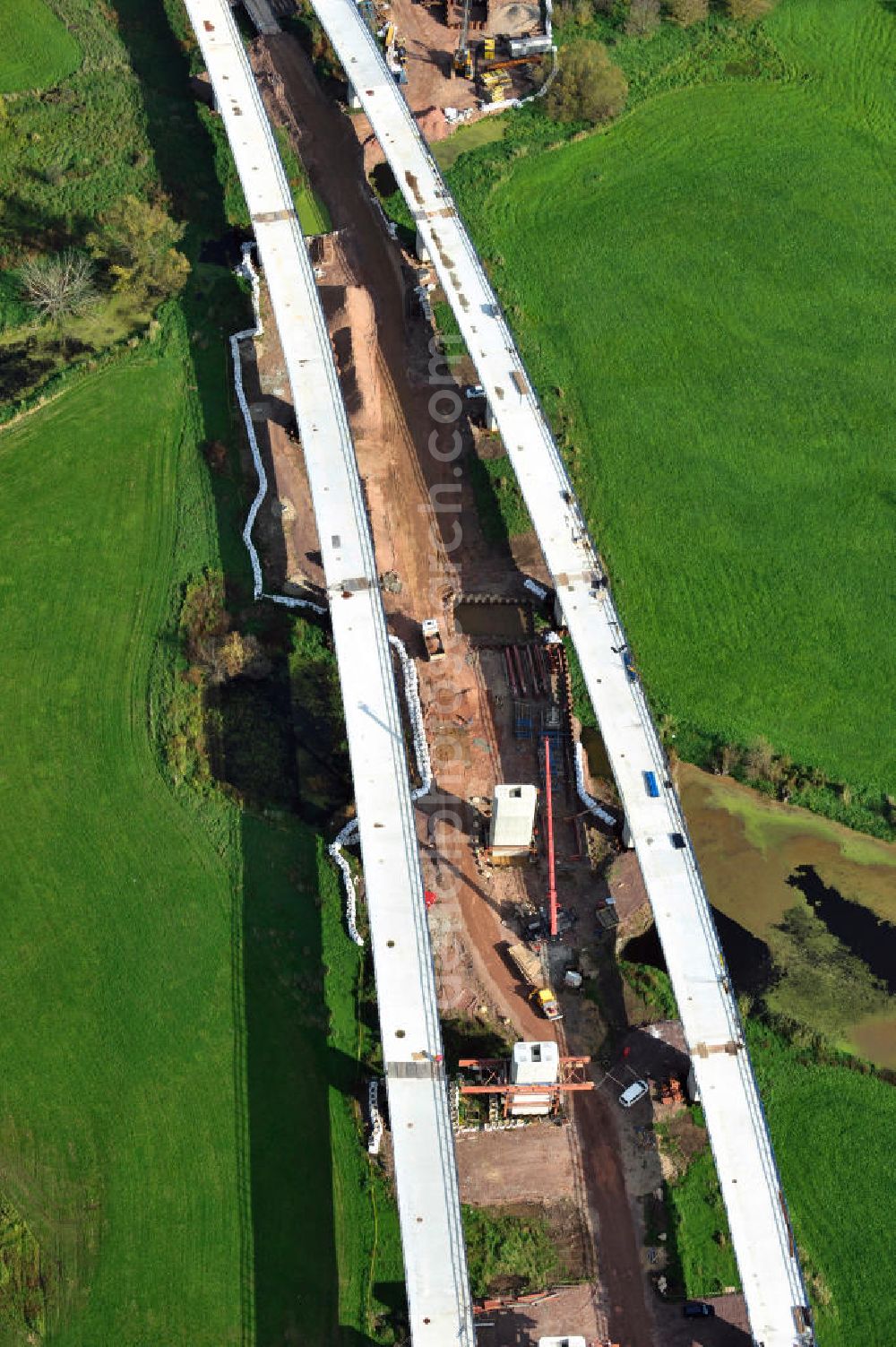 Rattmannsdorf from above - Vorschub- Bauarbeiten an der Saale-Elster-Talbrücke zwischen Ammendorf und Schkopau. Das Beton- Viadukt mit insgesamt 8, 5 Kilometern Länge wird teilweise mit großen Baugerüsten in so genannter Vor-Kopf-Bauweise errichtet. Die ICE - Neubaustrecke im Projekt VDE 8 der Deutschen Bahn und der DEGES soll 2015 in Betrieb gehen und wird das bisher längste Brückenbauwerk Deutschlands sein. Bauausführende Firmen sind die Hochtief Construction AG, Adam Hörnig, Gerdum und Breuer; Franki Grundbau; Doka Schalungstechniker; BBV Vorspanntechnik; Röro Traggerüstsysteme; Oevermann Hoch- und Tiefbau, Teupe & Söhne Gerüstbau GmbH, Alpine Bau, Kann Baustoffe und Arcelormittal. Die Bauüberwachung erfolgt durch das Ingenieurbüro Schüßler Plan. Construction site of the Saale-Elster-Talbrücke between Ammendorf and Schkopau. It will be 8, 5 km long and belongs to the Deutsche Bahn project VDE 8 and the DEGES. It should be finished in 2015. Its going to be the longest bridge in Germany. It is constructed by Hochtief Construction AG, Adam Hörnig, Gerdum und Breuer; Franki Grundbau; Doka Schalungstechniker; BBV Vorspanntechnik; Röro Traggerüstsysteme; Oevermann Hoch- und Tiefbau, Teupe & Söhne Gerüstbau GmbH, Alpine Bau, Kann Baustoffe und Arcelormittal.