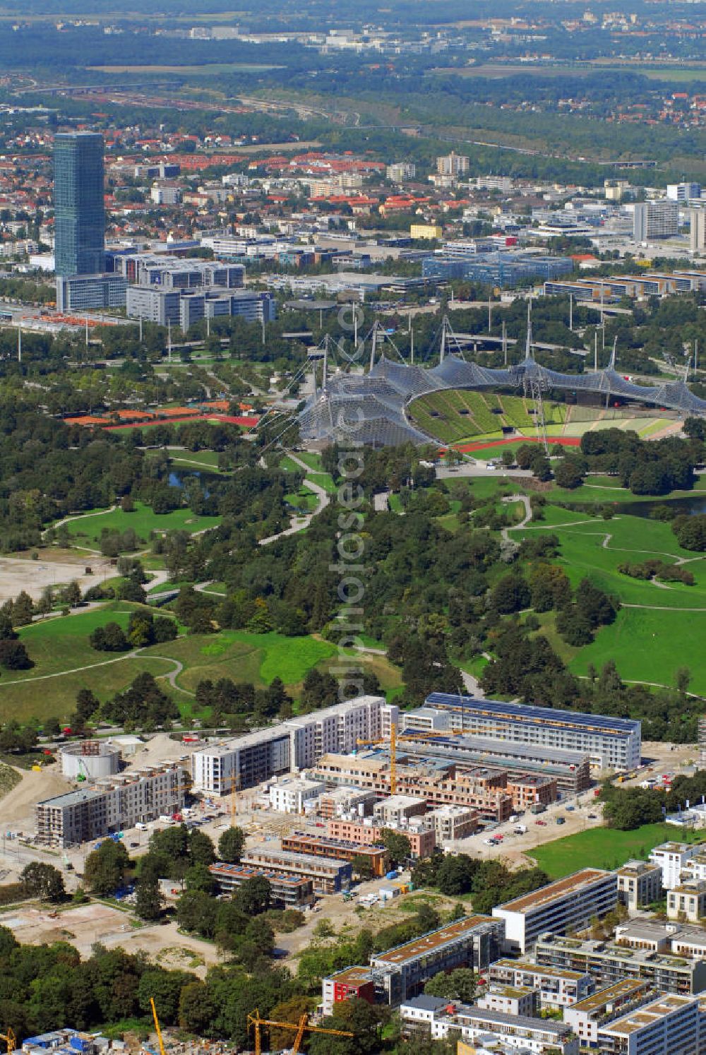 Aerial image München - Baustelle der Wohnanlage Ackermannstraße und Olympiapark mit Blick auf das Olympiastadion München. Im hinteren linken Bildrand ist der höchste Bürokomplex der Stadt, das Uptown, zu sehen. Kontakt: cf Claudia Fischer Architekten, kaiserplatz 12 80803 München, Tel. +49(0)89 33066 265, Fax +49(0)89 33066 267, Email: cfarchitekten@gmx.net; Olympiapark München GmbH, Spiridon-Louis-Ring 21, 80809 München, Tel. +49(0)8930 67 0, Fax +49(0)8930 6722 22, Email: info@olympiapark-muenchen.de; Uptwon: Ingenhoven Architekten, Plange Mühle 1, 40221 Düsseldorf, Tel. +43(0)211 30101 01, Fax +43(0)211 30101 31, Email: info@ingenhovenarchitekten.de; ATP Architekten und Ingenieure, Innsbruck, Heiliggeiststr. 16, A 6020 Innsbruck, Tel. +43(0)512 261 870, Fax +43(0)512 261 864, Email: info@atp.ag; Wayss & Freytag Schlüsselfertigbau AG Geschäftsbereich Allgemeiner Hochbau, Eschborner Landstraße 55, 60489 Frankfurt am Main, Tel. +49(0)69 97901 0, Fax +49(0)69 97901 750, Email: info@wf-sfbau.de