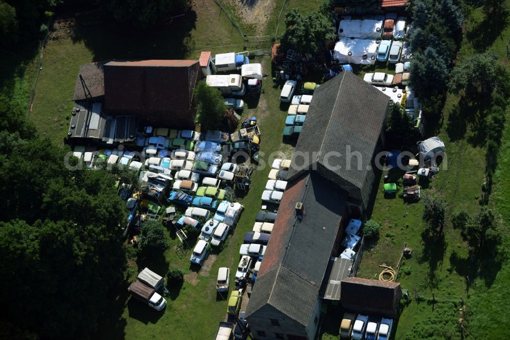 Gräfenhainichen from the bird's eye view: Farm in the North of the Tornau part of the town of Graefenhainichen in the state of Saxony-Anhalt. The agricultural estate is located at a forest and surrounded by meadows. Several cars of the Trabant brand or Trabi are located on the compound