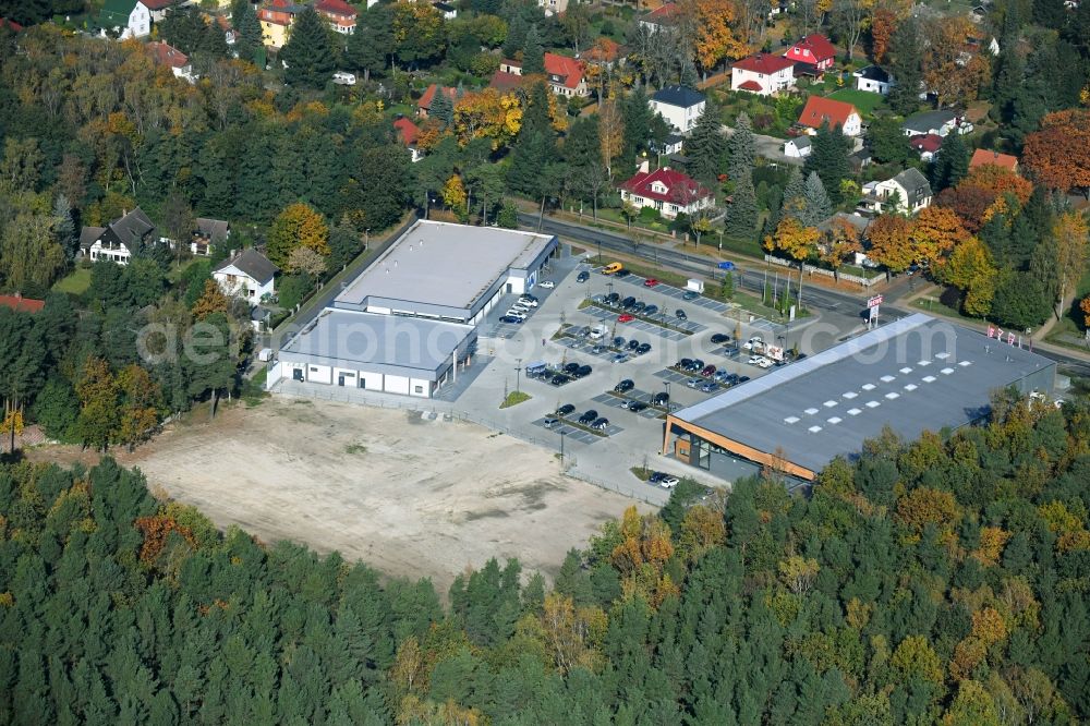 Hohen Neuendorf from the bird's eye view: Construction site of a new shopping center and store of the Supermarket REWE in Hohen Neuendorf in the state of Brandenburg. A new shopping facility with stores is being built as part of the regeneration of the shopping center HDZ on Schoenfliesser Strasse. The project is carried out by GVG Projektentwicklungsgesellschaft mbH