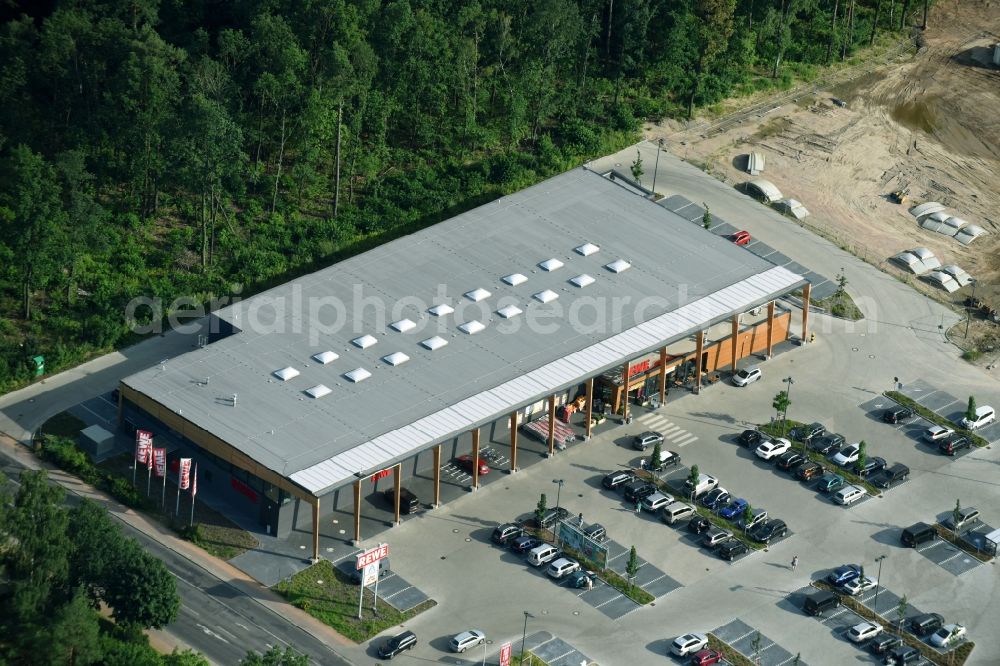 Hohen Neuendorf from the bird's eye view: Construction site of a new shopping center and store of the Supermarket REWE in Hohen Neuendorf in the state of Brandenburg. A new shopping facility with stores is being built as part of the regeneration of the shopping center HDZ on Schoenfliesser Strasse. The project is carried out by GVG Projektentwicklungsgesellschaft mbH