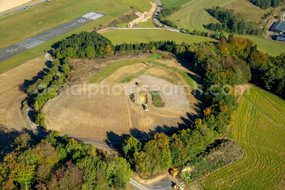 Meschede from the bird's eye view: Construction site with development works and embankments works on unbuilt land near the nature reserve Steinbruch Schueren in Meschede in the state of North Rhine-Westphalia. In the background a take - off and landing runway of the airfield Schueren