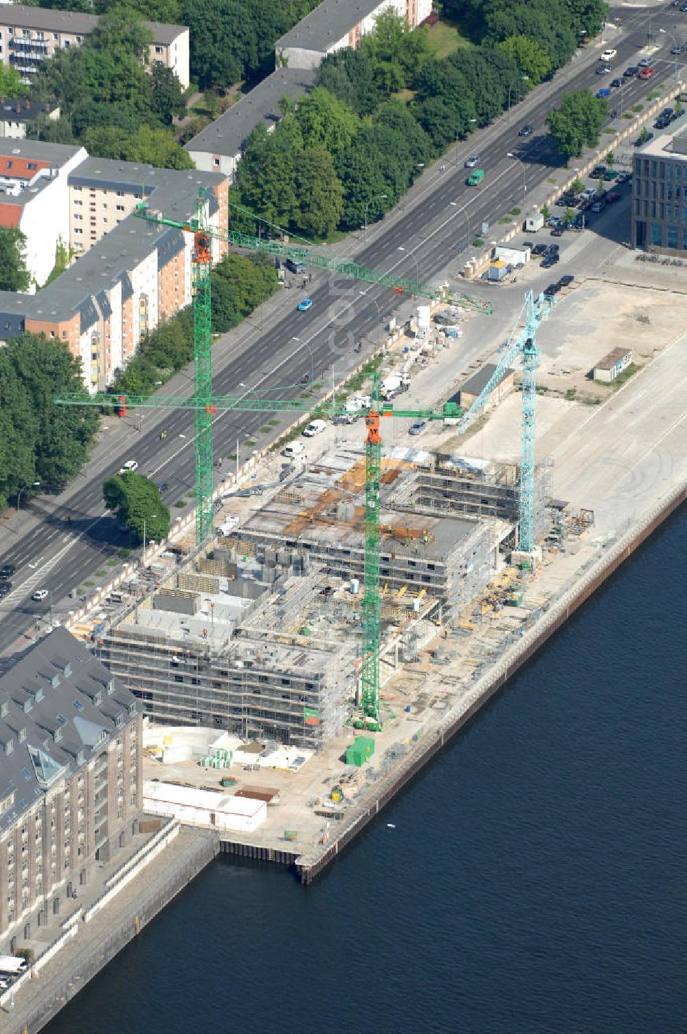 Berlin from the bird's eye view: Blick über den Osthafen auf die Baustelle für ein 4-Sterne-Hotel in der Stralauer Allee in Berlin-Friedrichshain. Das Hotel wird direkt neben den ehemaligen Getreidespeicher gebaut, Bauherr: NH Group Desk, Kontakt: