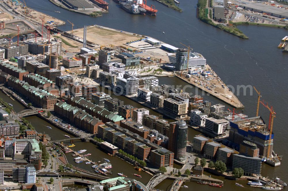 Aerial photograph Hamburg - Blick über die Speicherstadt auf die Baustelle der neu entstehenden Hafen City mit Bauprojekten Am Sandtorkai, Dalmannkai, Am Sandtorpark, Strandkai und am Überseequartier. Die HafenCity ist ein Hamburger Stadtteil im Bezirk Hamburg-Mitte. Der 155 Hektar große Stadtteil (mit 60 Hektar Nettobauland) soll neben Büroflächen für mehr als 40.000 Arbeitsplätze, die zu einem Teil schon fertiggestellt sind, auch Wohnraum für 12.000 Einwohner in 5.500 Wohnungen bieten und ist damit das größte laufende Vorhaben zur Stadtentwicklung von Hamburg. Allgemeine Informationen: