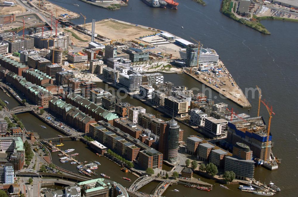 Hamburg from the bird's eye view: Blick über die Speicherstadt auf die Baustelle der neu entstehenden Hafen City mit Bauprojekten Am Sandtorkai, Dalmannkai, Am Sandtorpark, Strandkai und am Überseequartier. Die HafenCity ist ein Hamburger Stadtteil im Bezirk Hamburg-Mitte. Der 155 Hektar große Stadtteil (mit 60 Hektar Nettobauland) soll neben Büroflächen für mehr als 40.000 Arbeitsplätze, die zu einem Teil schon fertiggestellt sind, auch Wohnraum für 12.000 Einwohner in 5.500 Wohnungen bieten und ist damit das größte laufende Vorhaben zur Stadtentwicklung von Hamburg. Allgemeine Informationen: