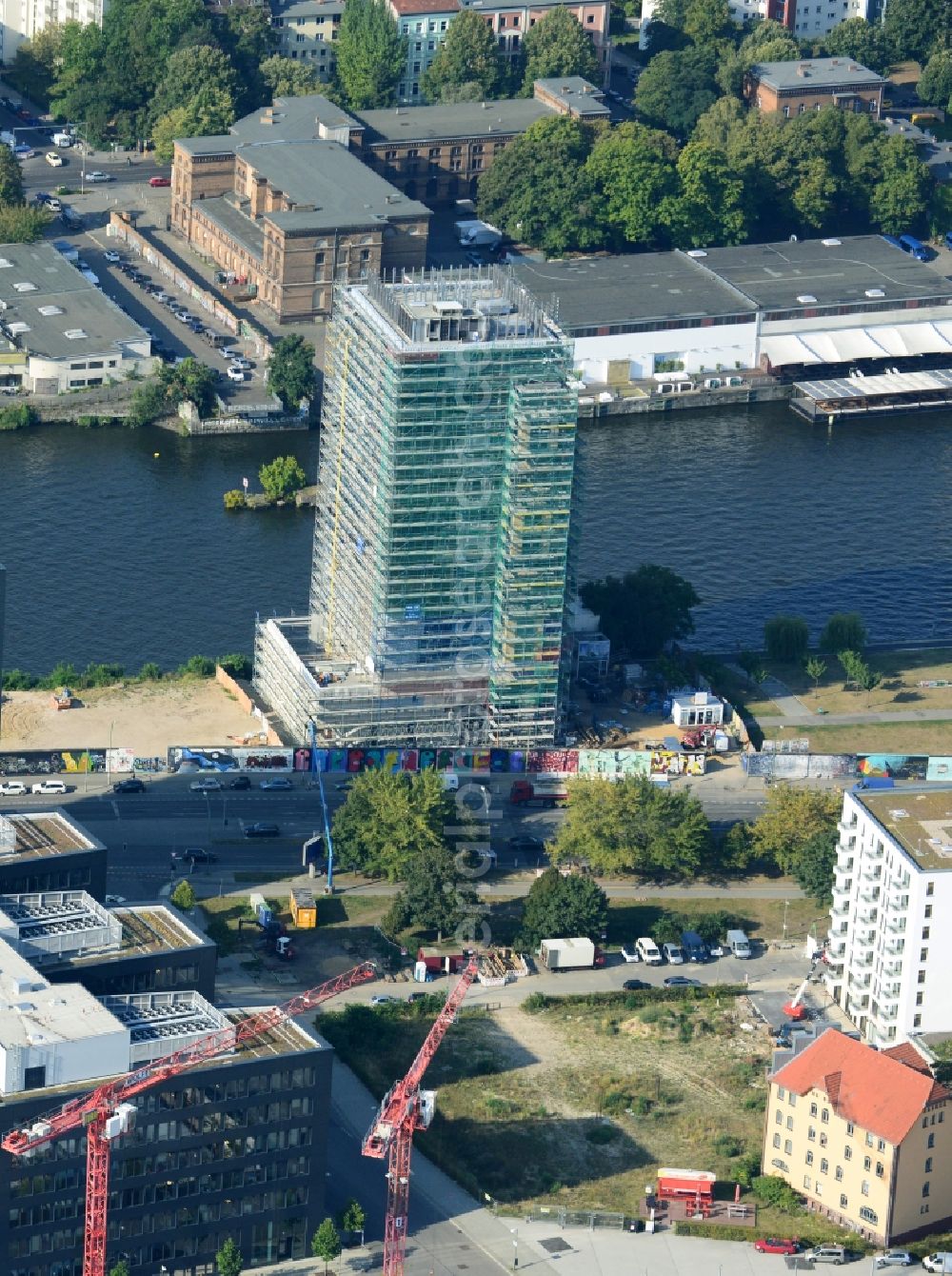 Berlin from above - Construction site of Project Living Levels at Muhlenstrasse on the banks of the River Spree in Berlin - Friedrichshain. On the grounds of the Berlin Wall border strip at the EastSideGallery, the company Living Bauhaus is building a futuristic high-rise residential. The real estate service company City & Home GmbH manages the available apartments