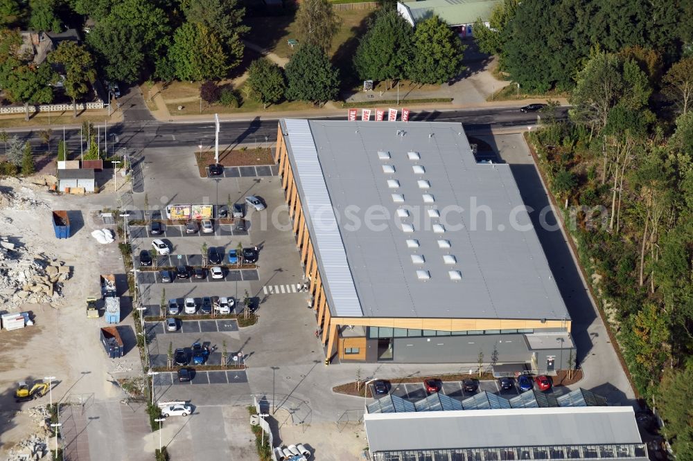 Hohen Neuendorf from the bird's eye view: Construction site of a new shopping center and store of the Supermarket REWE in Hohen Neuendorf in the state of Brandenburg. A new shopping facility with stores is being built as part of the regeneration of the shopping center HDZ on Schoenfliesser Strasse. The project is carried out by GVG Projektentwicklungsgesellschaft mbH